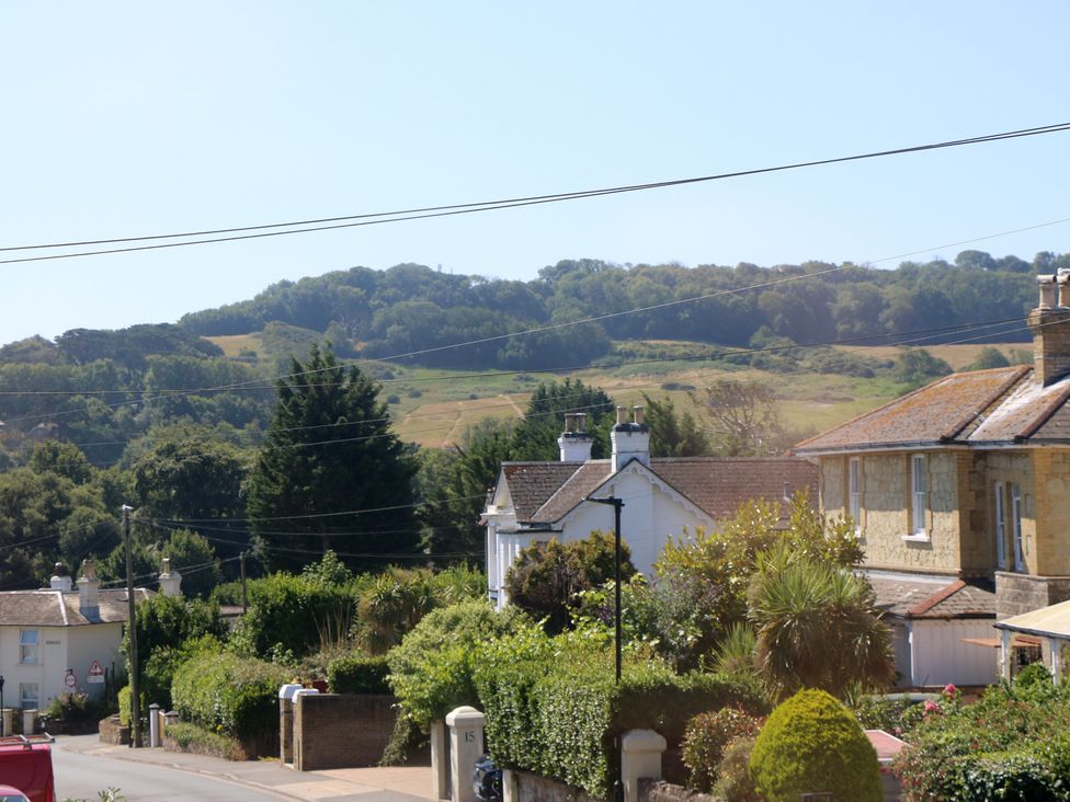 A view of houses and trees with hills in the background at Bay Tree Cottage in Shanklin