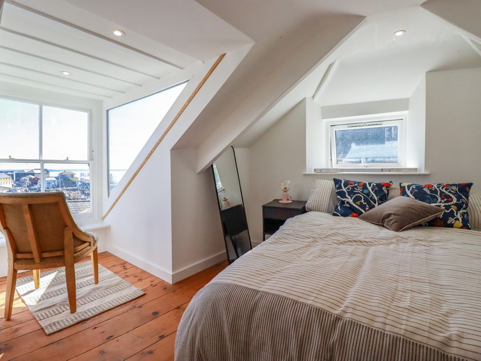 A bedroom with a bed and chair at Whalebone Cottage in St. Austell