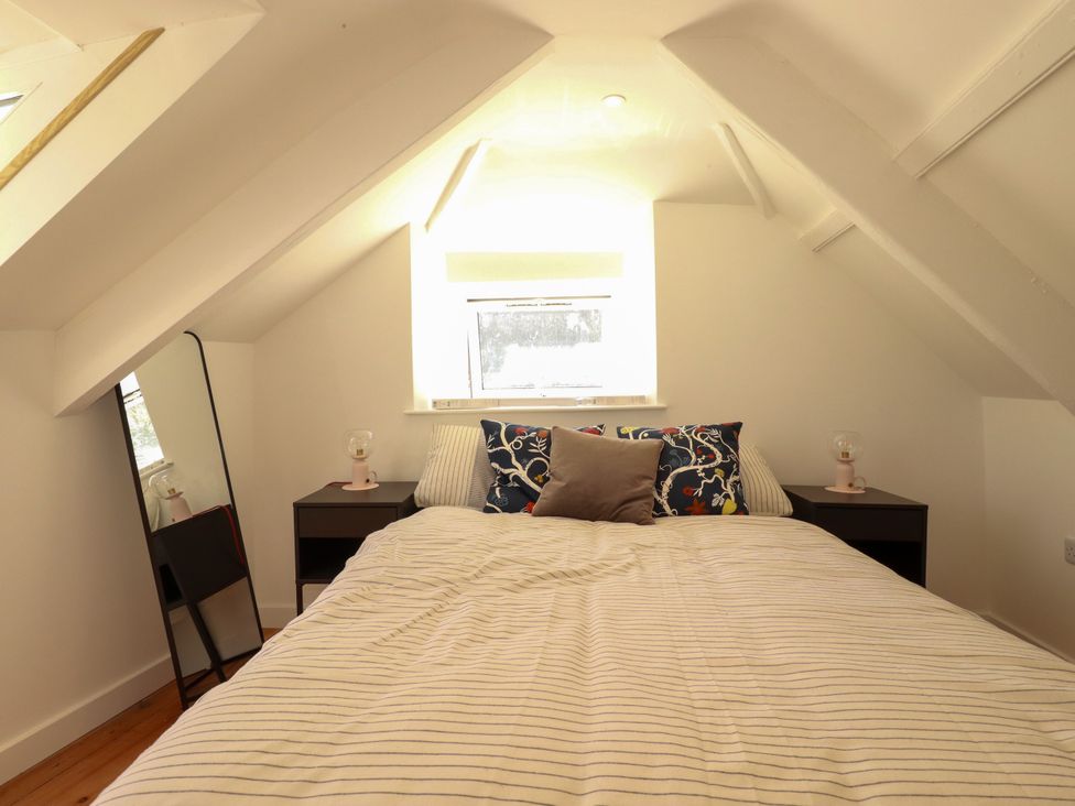 A bedroom with a bed and nightstands at Whalebone Cottage in St. Austell