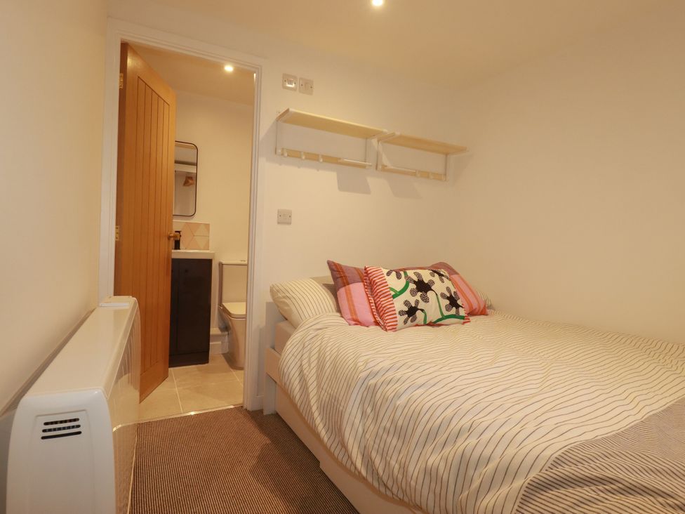 A bedroom with a bed and access to a bathroom at Whalebone Cottage in St. Austell