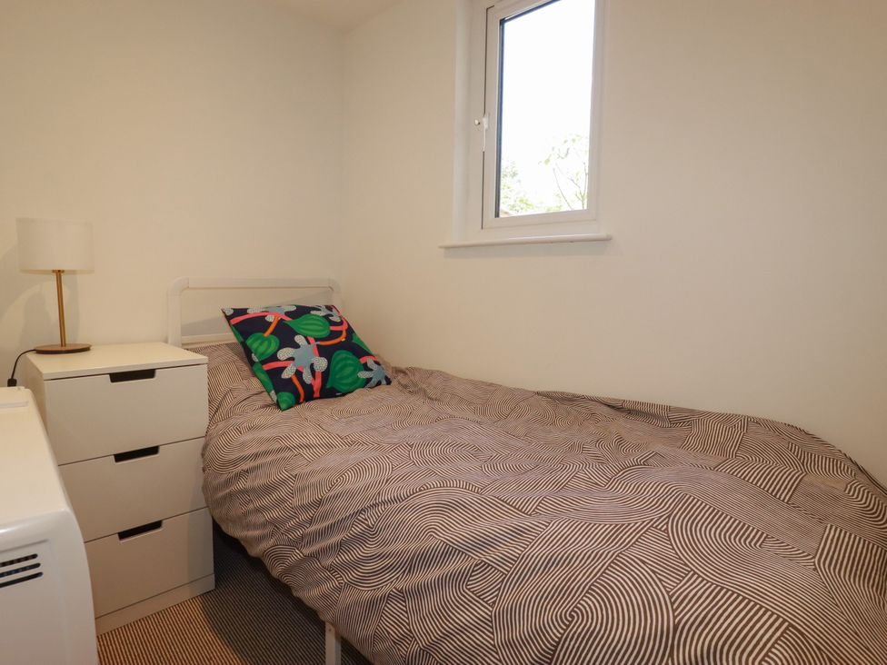 A bedroom with a bed and a nightstand at Whalebone Cottage in St. Austell