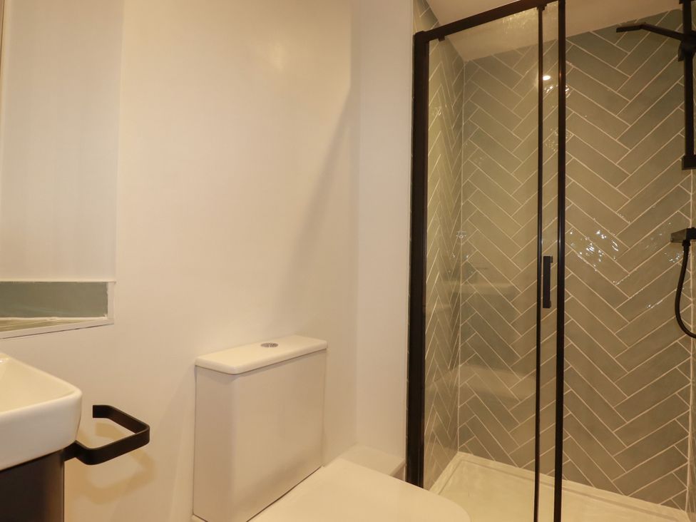 A bathroom with a shower and toilet at Whalebone Cottage St. Austell