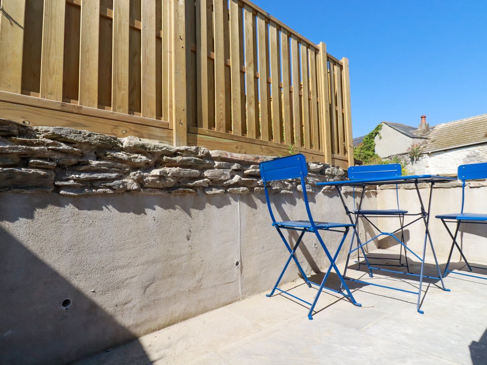 An outdoor area with a stone wall and blue metal furniture at Whalebone Cottage St. Austell