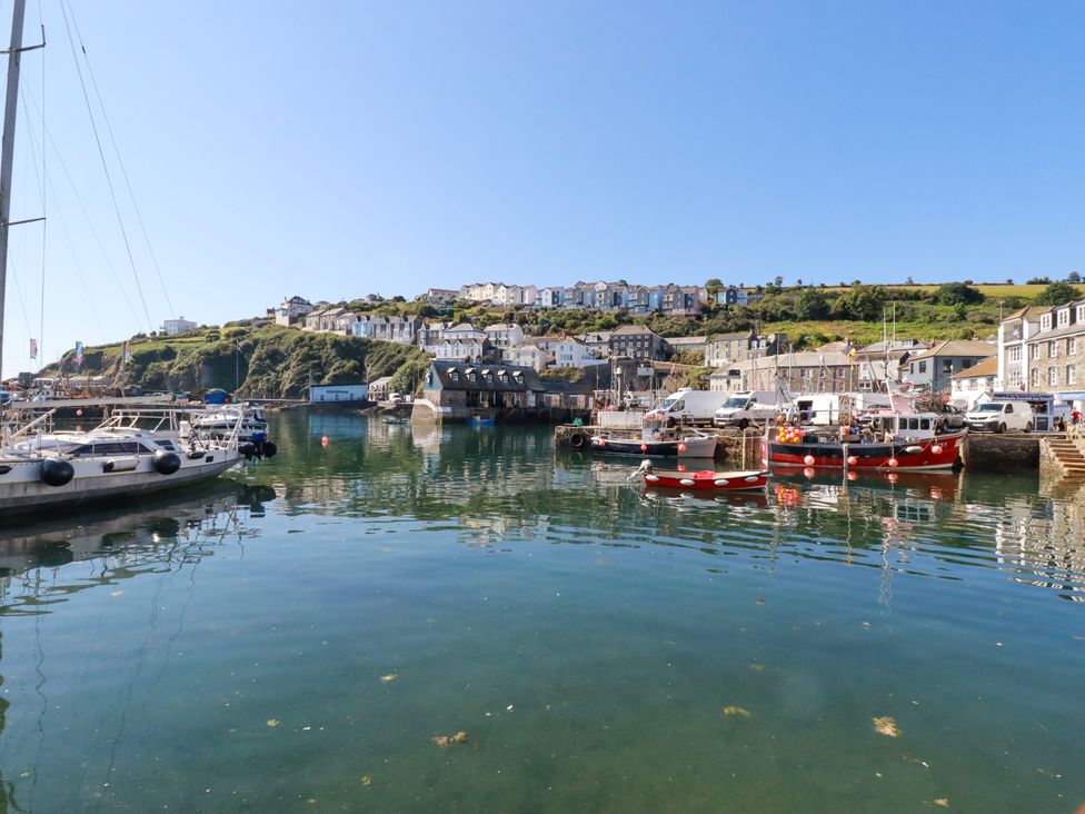 A harbor with boats and buildings near the water at Whalebone Cottage in St. Austell
