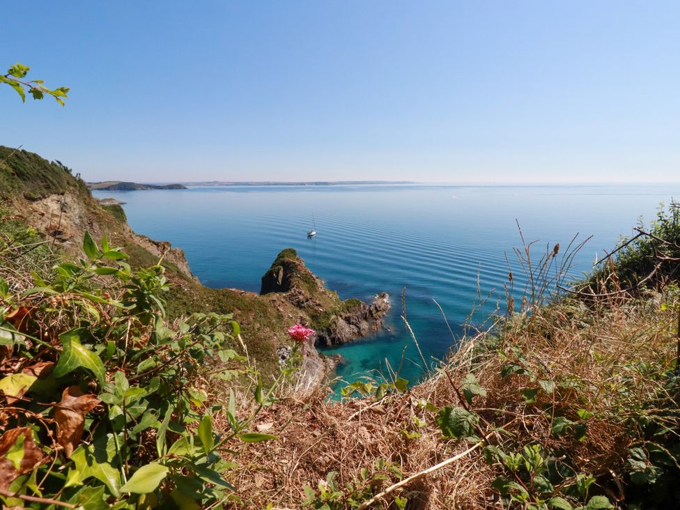 A coastal scene with a boat in the ocean at Whalebone Cottage in St. Austell
