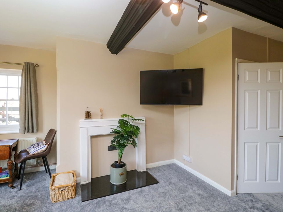A living room with a television and a table at 3 Woods Farm House in Chippenham