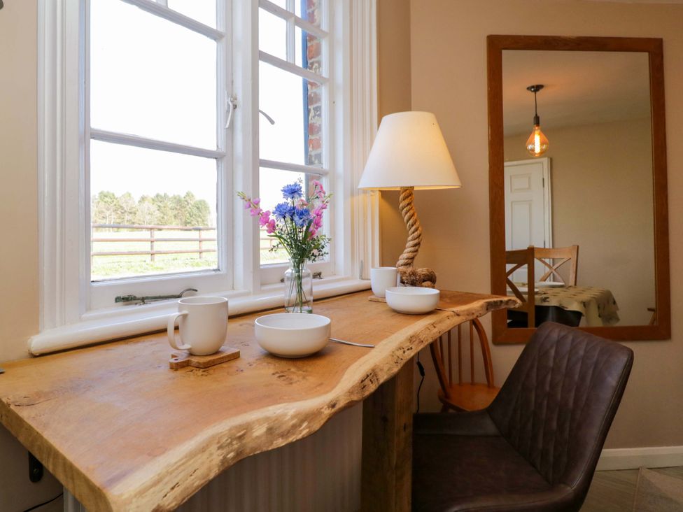 A dining room with a wooden table and a lamp at 3 Woods Farm House in Chippenham