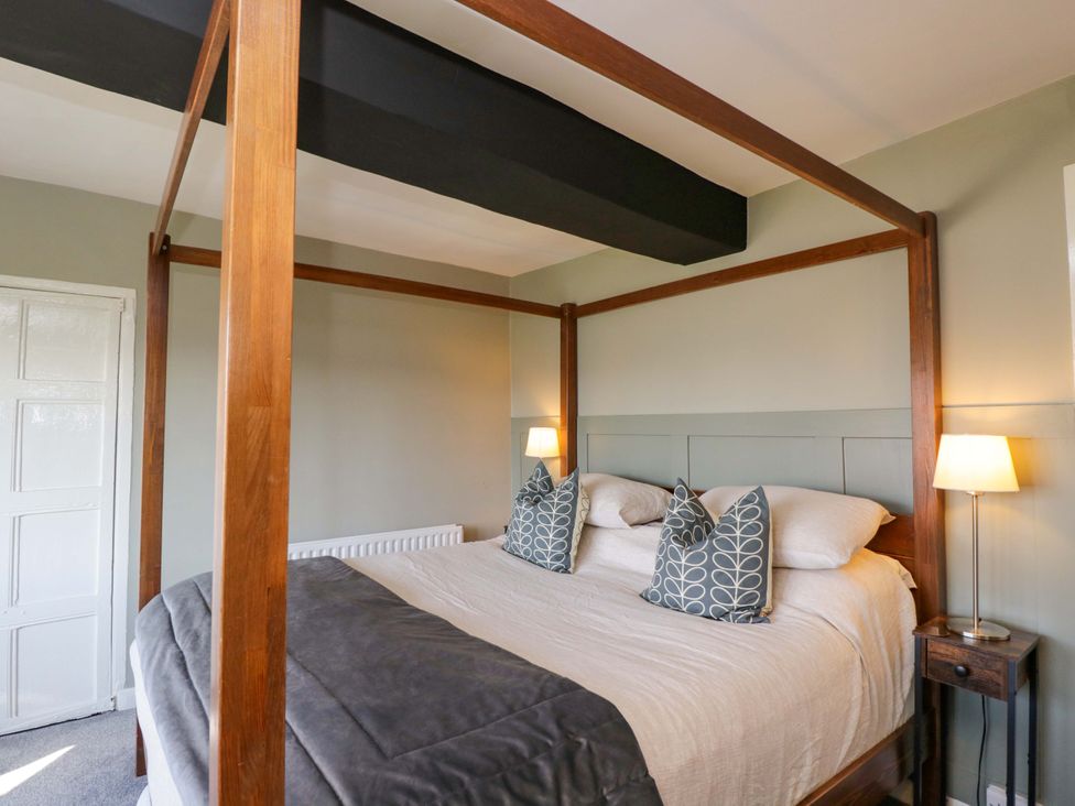 A bedroom with a four-poster bed and a nightstand at 3 Woods Farm House in Chippenham