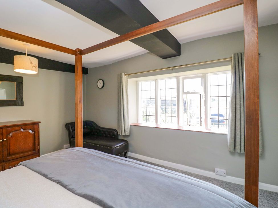 A bedroom with a four-poster bed and an armchair at 3 Woods Farm House in Chippenham