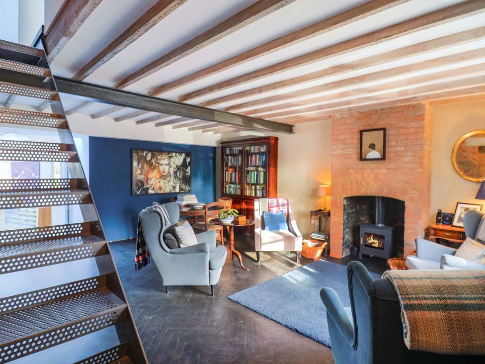 A living room with a staircase and bookshelf at Bredy Cottages in Burton Bradstock