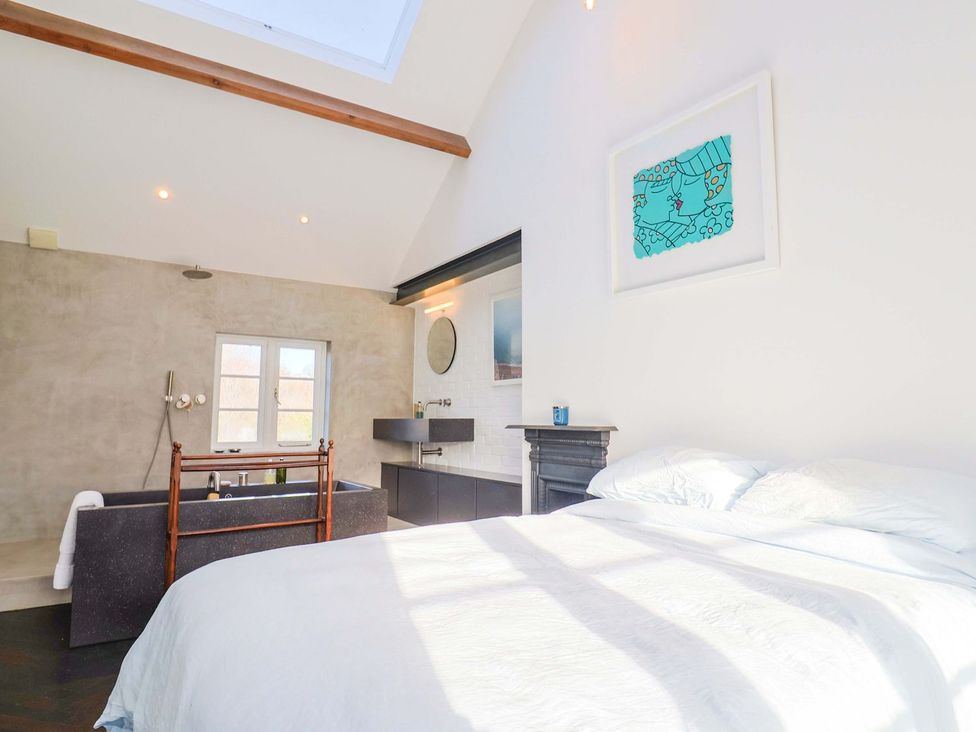 A bedroom with a bed and a bathtub at Bredy Cottages Burton Bradstock