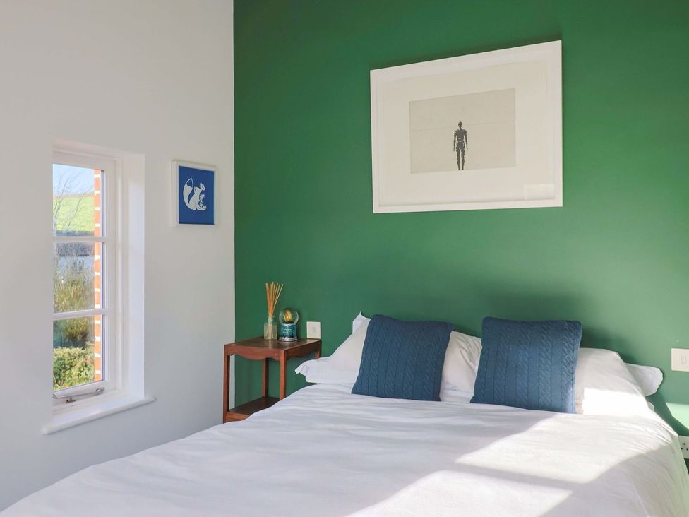 A bedroom with a bed and wall art at Bredy Cottages in Burton Bradstock