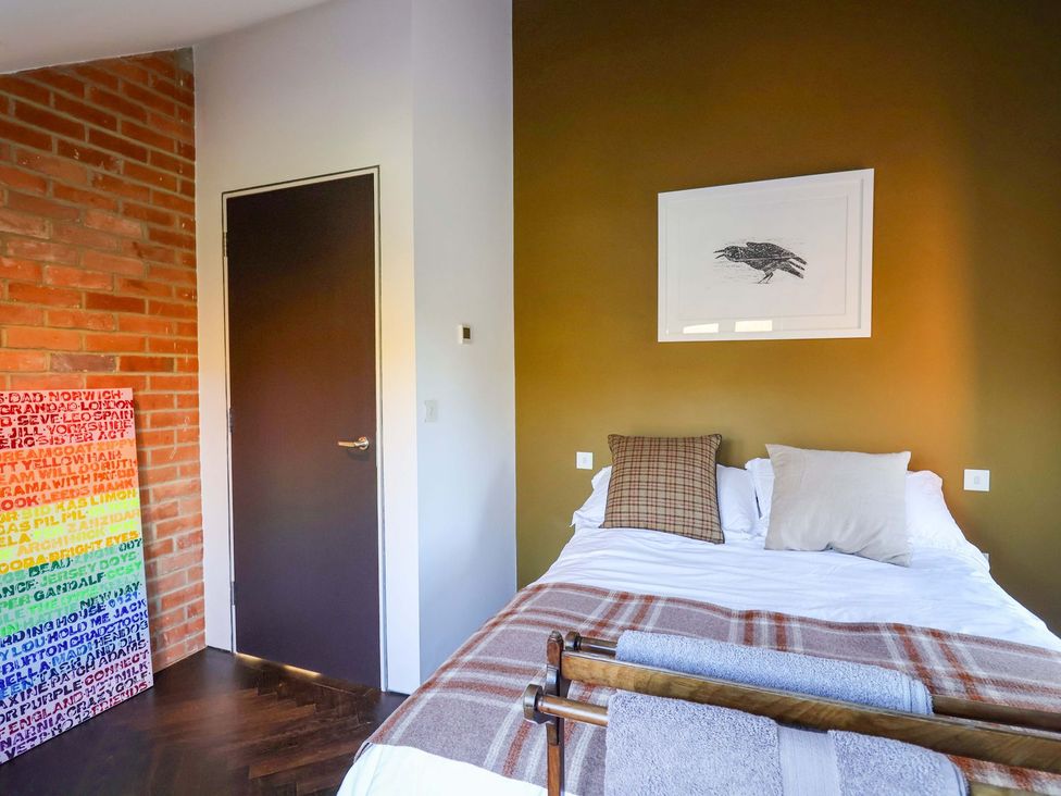 A bedroom with a bed and wall art at Bredy Cottages, Burton Bradstock