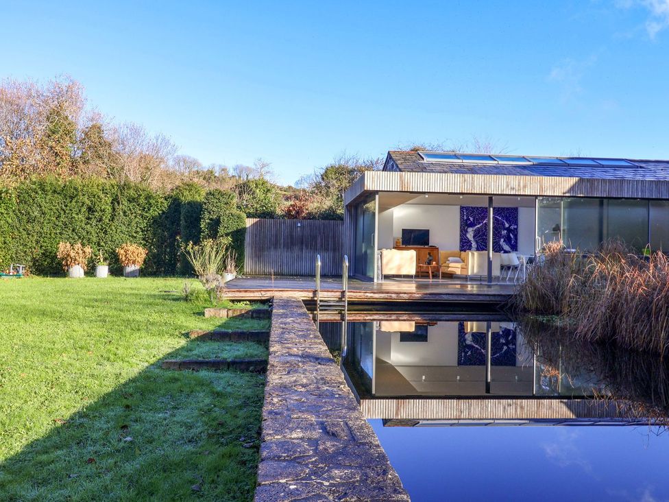 An outdoor view of a house with garden and water feature at Bredy Cottages in Burton Bradstock