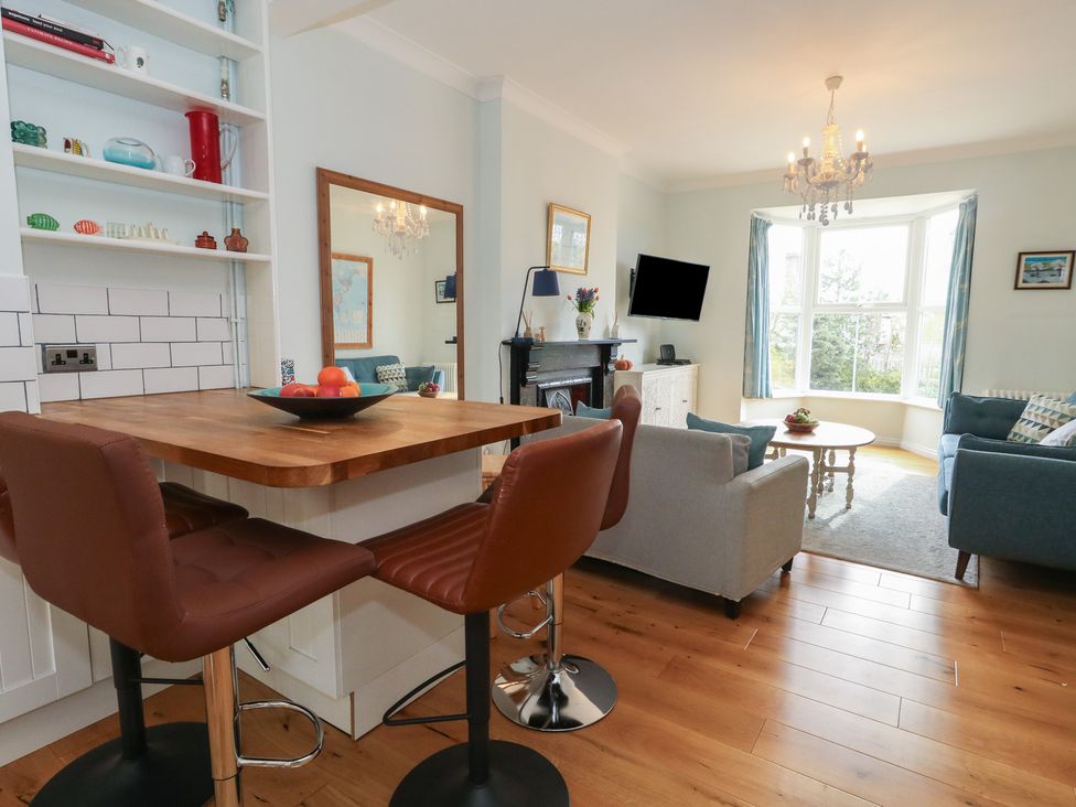 A living room with a kitchen table and bar stools at Millmead House in Portesham