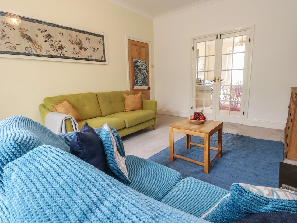 A living room with a green sofa and wooden coffee table at Millmead House in Portesham