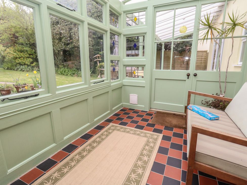 A conservatory with green walls and a bench at Millmead House in Portesham