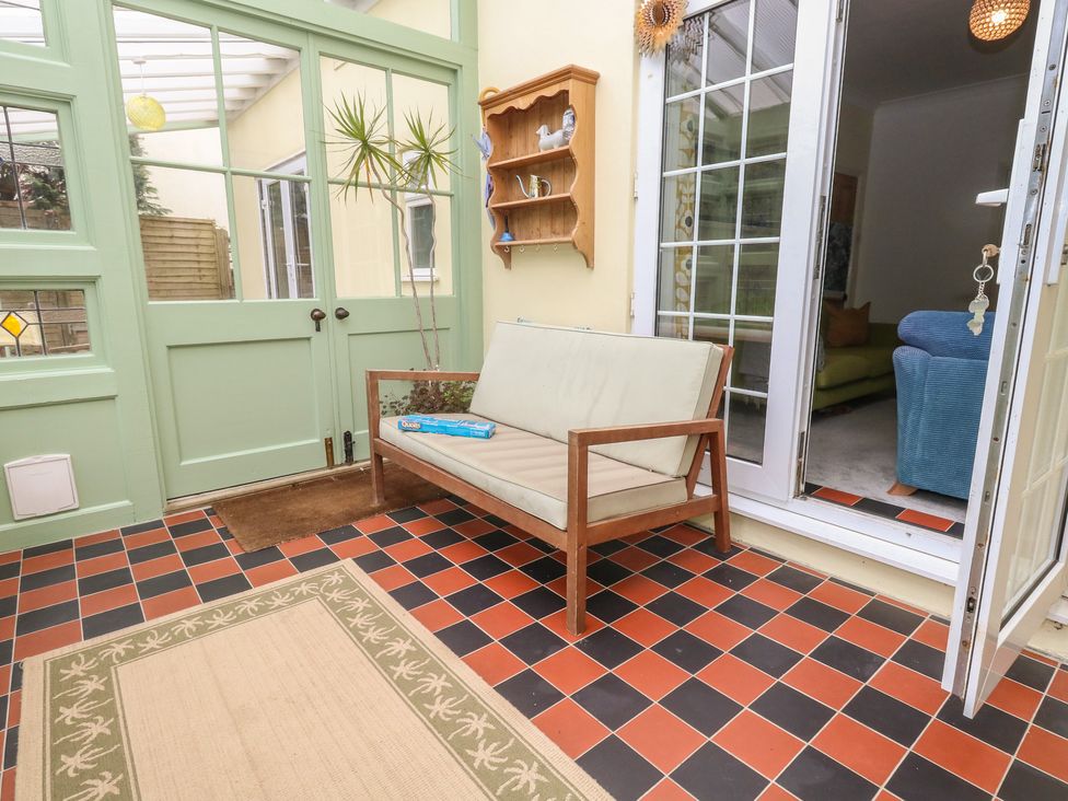 A conservatory with a sofa and a shelf at Millmead House in Portesham