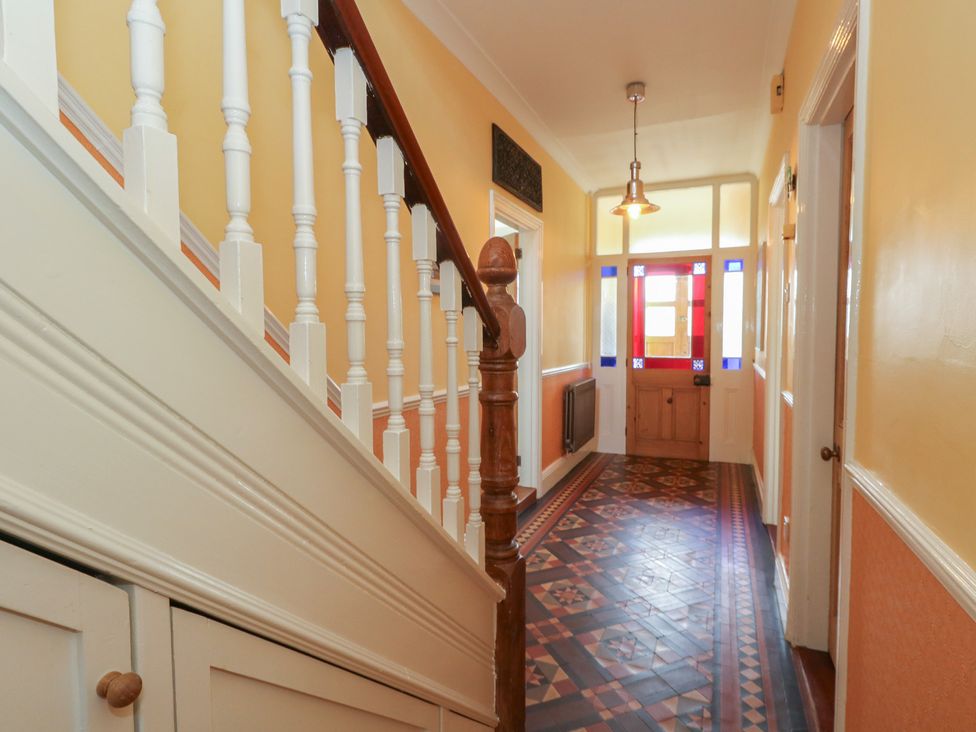 A hallway with a staircase and wooden front door at Millmead House Portesham