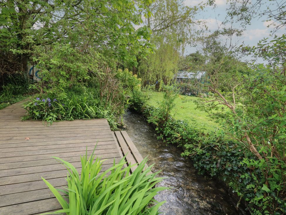 An outdoor area with a wooden deck and stream at Millmead House Portesham