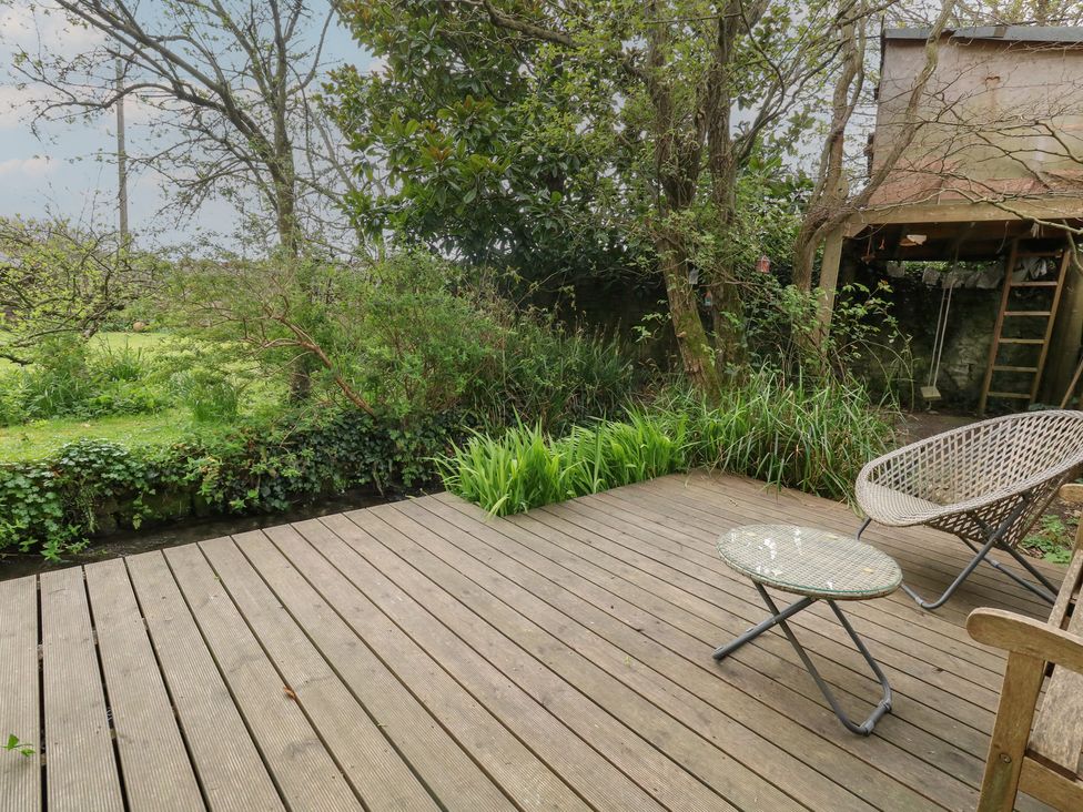 A garden area with decking, a chair, and table at Millmead House Portesham