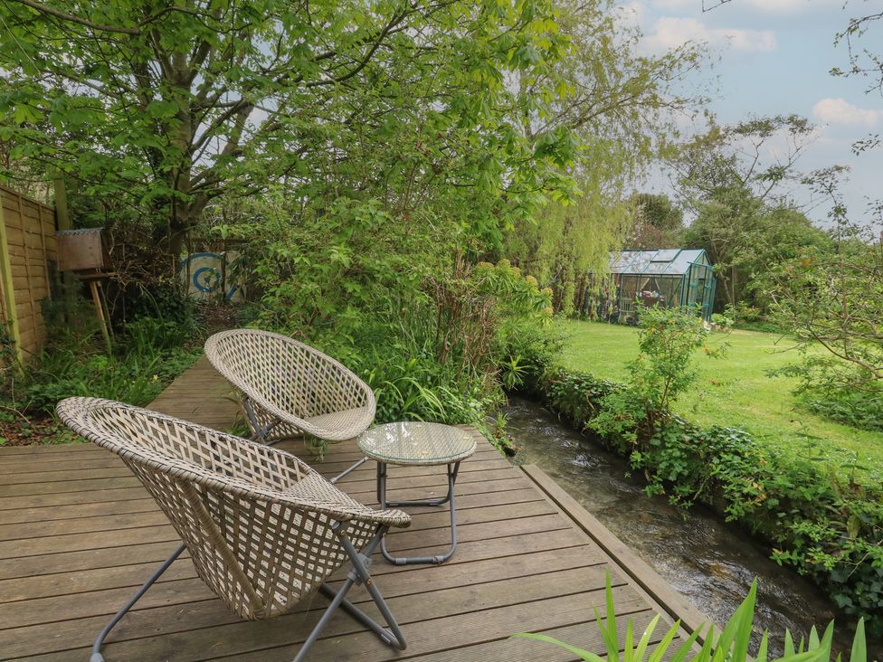 A garden with two chairs and a table near a stream at Millmead House Portesham
