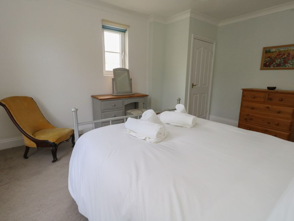 A bedroom with a bed, chair, dresser, and mirror at Millmead House in Portesham