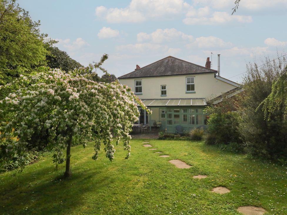 A house with a garden and flowering tree at Millmead House in Portesham