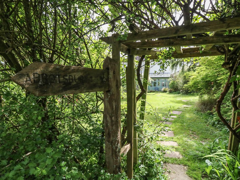 A garden with a signpost and a pathway at Millmead House Portesham