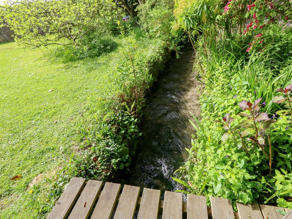 A garden with a stream and wooden decking at Millmead House Portesham