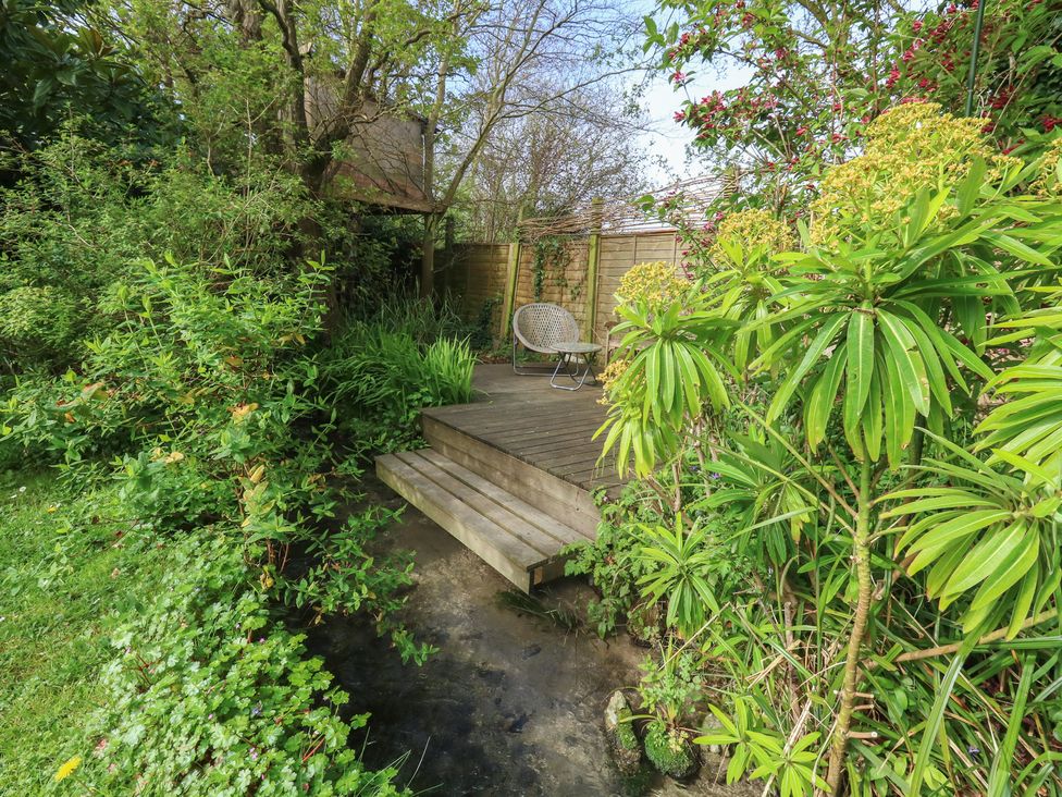 A garden with decking and a chair at Millmead House Portesham