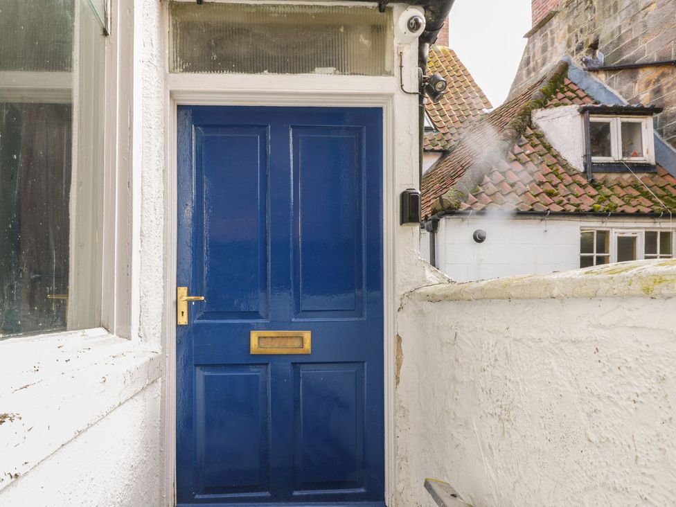 A blue door with a mail slot and security camera at 47A Baxtergate in Whitby