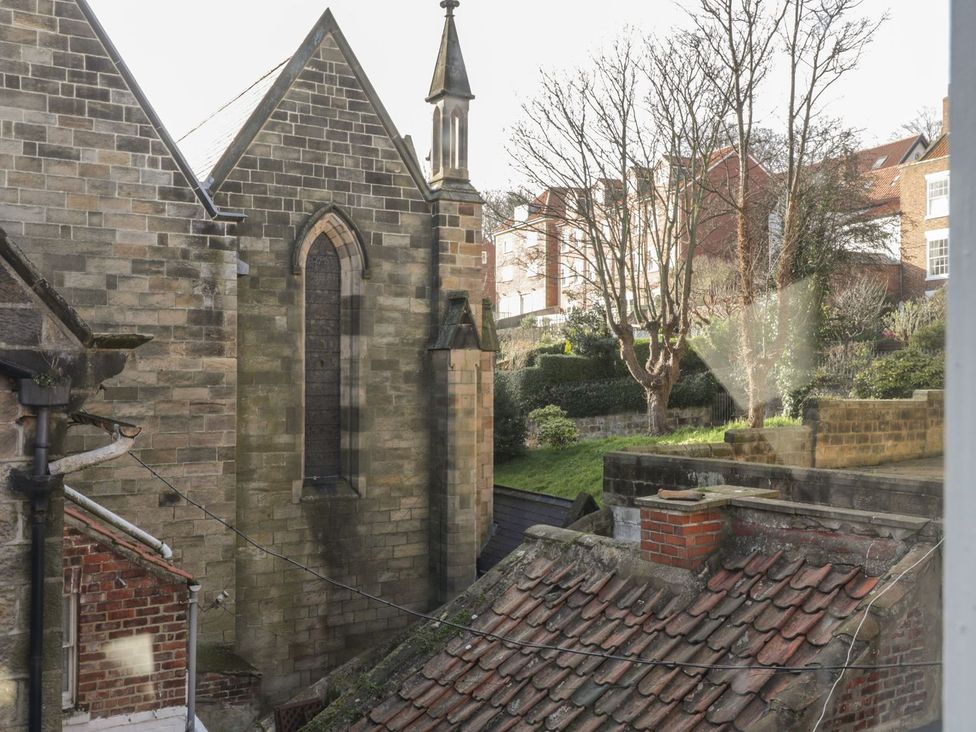 A view featuring a church building, roofs, and trees at 47A Baxtergate, Whitby