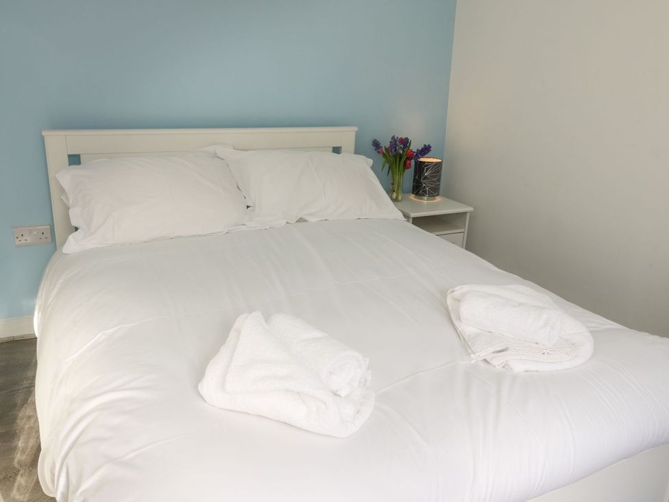 A bedroom with a bed and flowers on a bedside table at 47A Baxtergate in Whitby