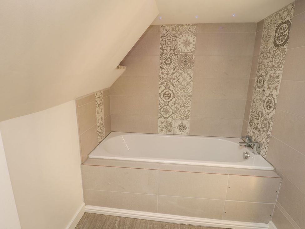 A bathroom featuring a bathtub and tiled walls at 47A Baxtergate in Whitby