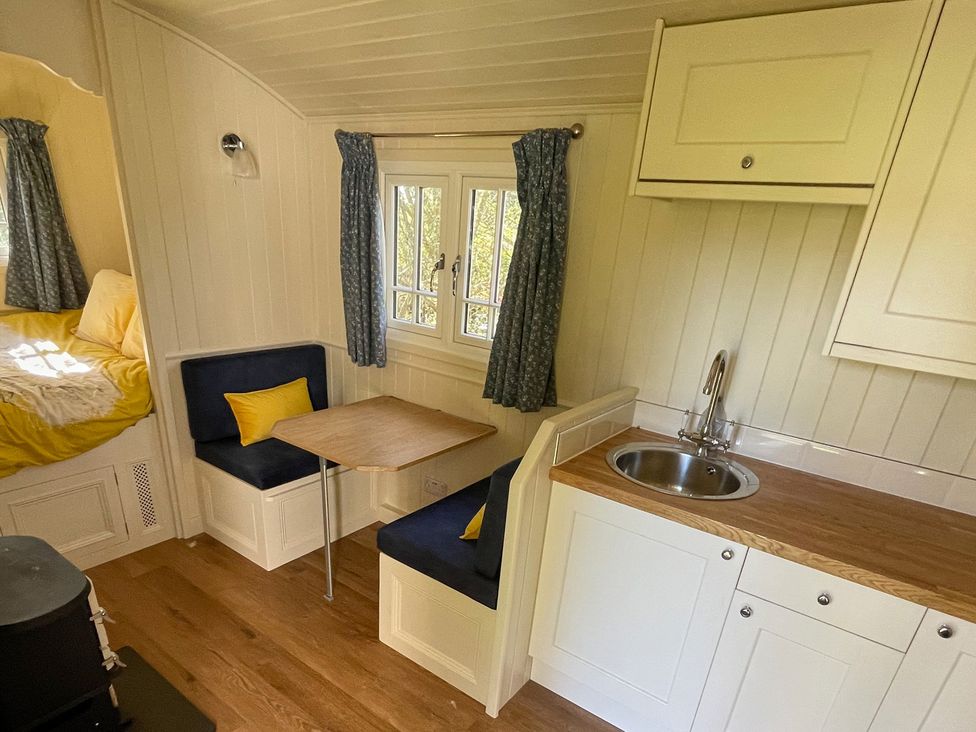 A kitchen area with a table and seating at The Shephards Hut