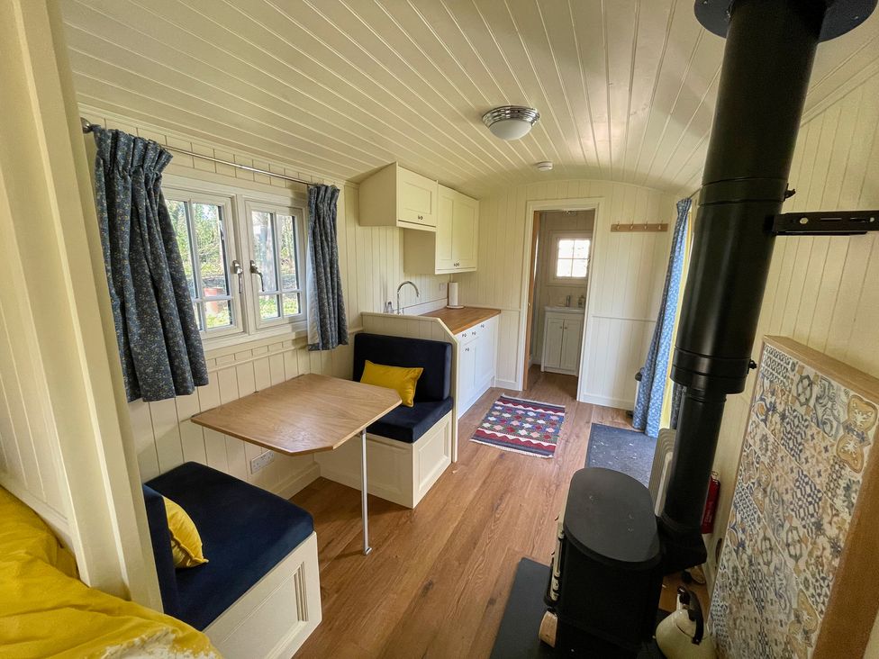 A kitchen with table and bench seating at The Shephards Hut