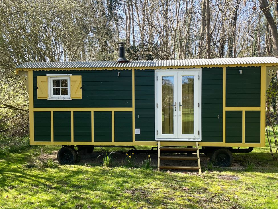 A tiny house with a green exterior and white doors at The Shephards Hut