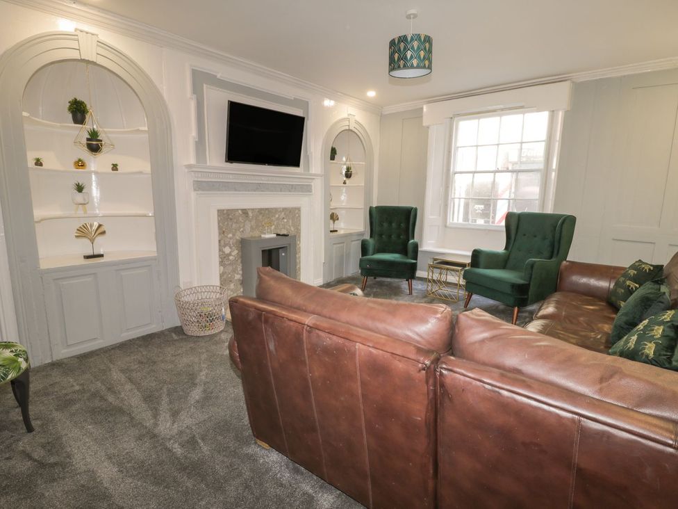A living room with green armchairs and a brown sofa at 47 Baxtergate in Whitby