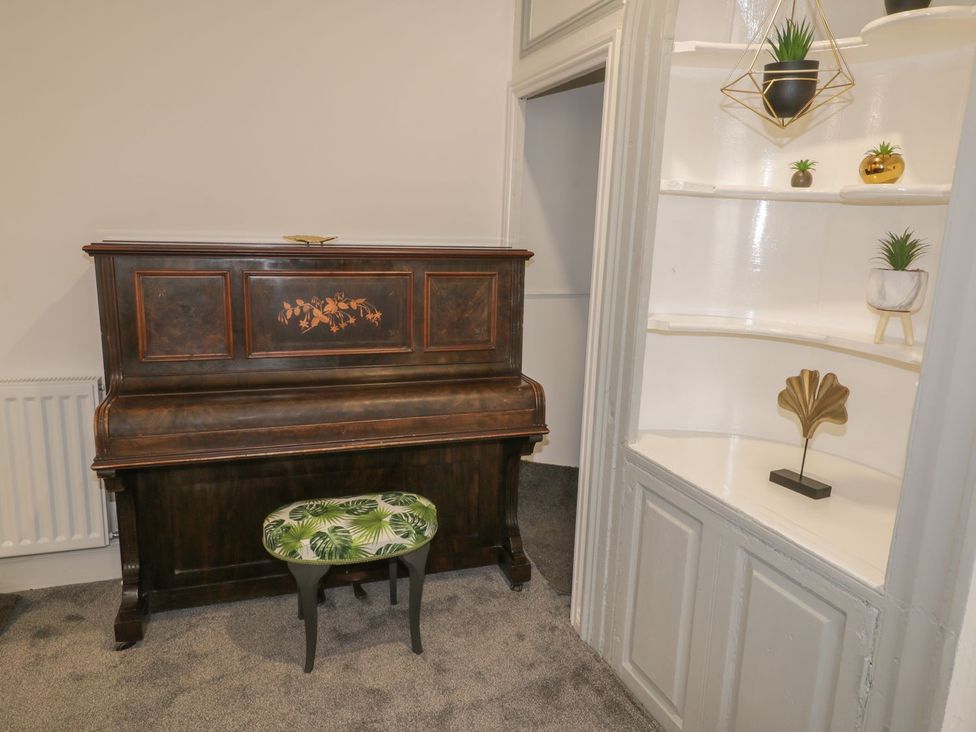 A living room with a piano and shelf at 47 Baxtergate in Whitby