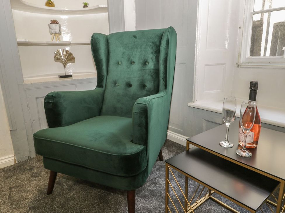 A living room with a green armchair and a side table at 47 Baxtergate, Whitby