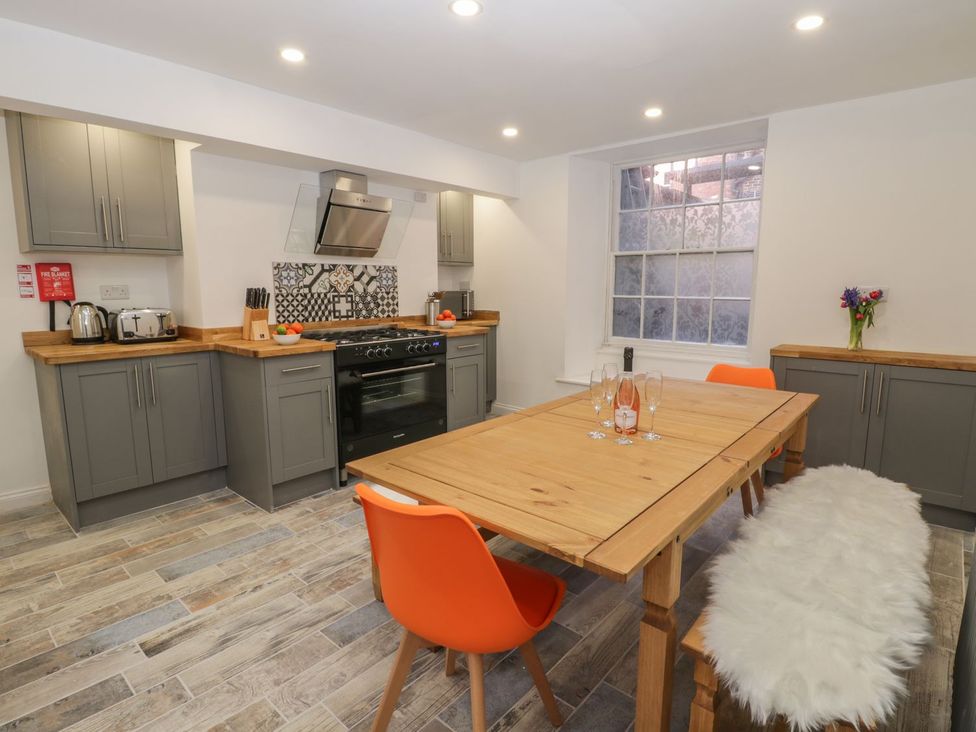 A kitchen with a dining table and orange chairs at 47 Baxtergate in Whitby