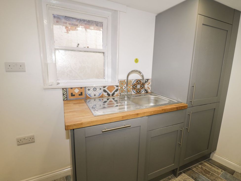 A kitchen with a stainless steel sink and wall tiles at 47 Baxtergate, Whitby