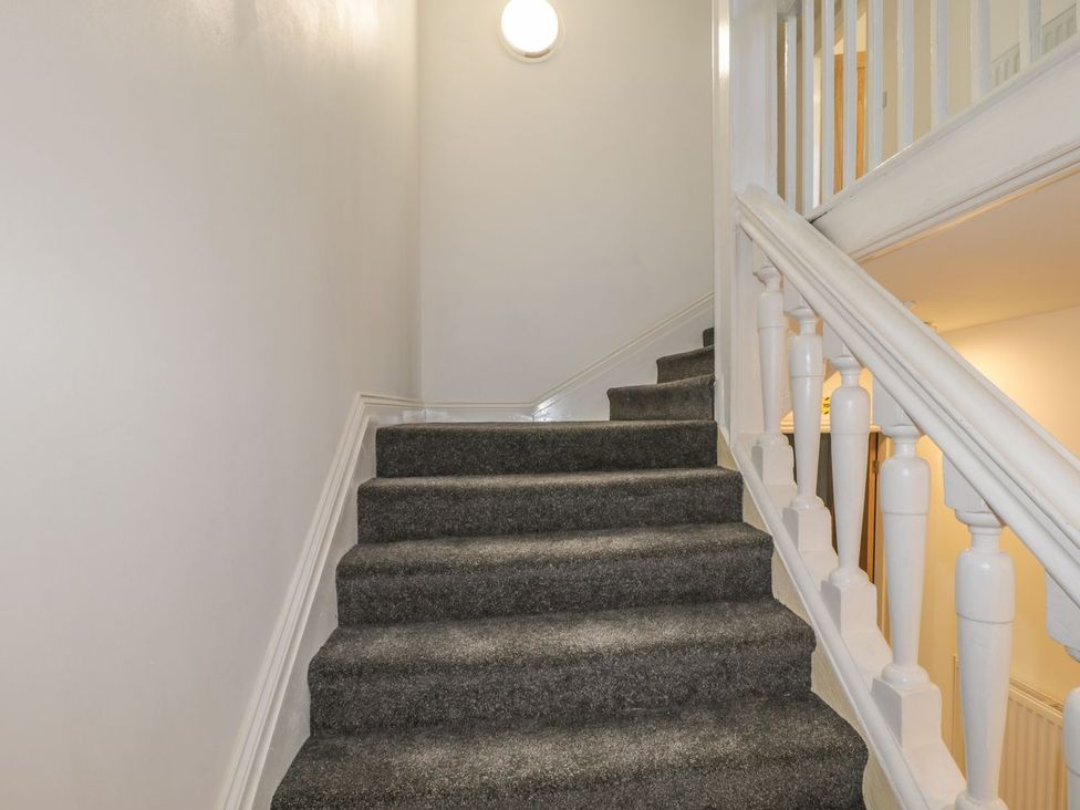 A staircase with carpet and handrail at 47 Baxtergate in Whitby