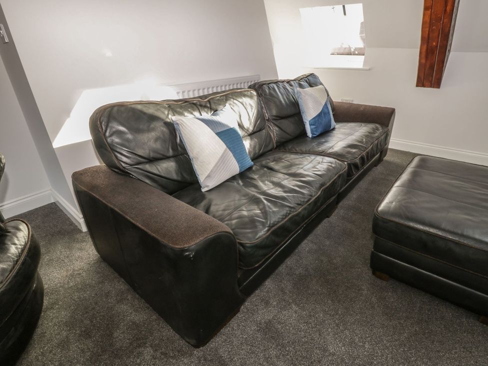 A living room with a leather sofa and cushions at 47 Baxtergate in Whitby