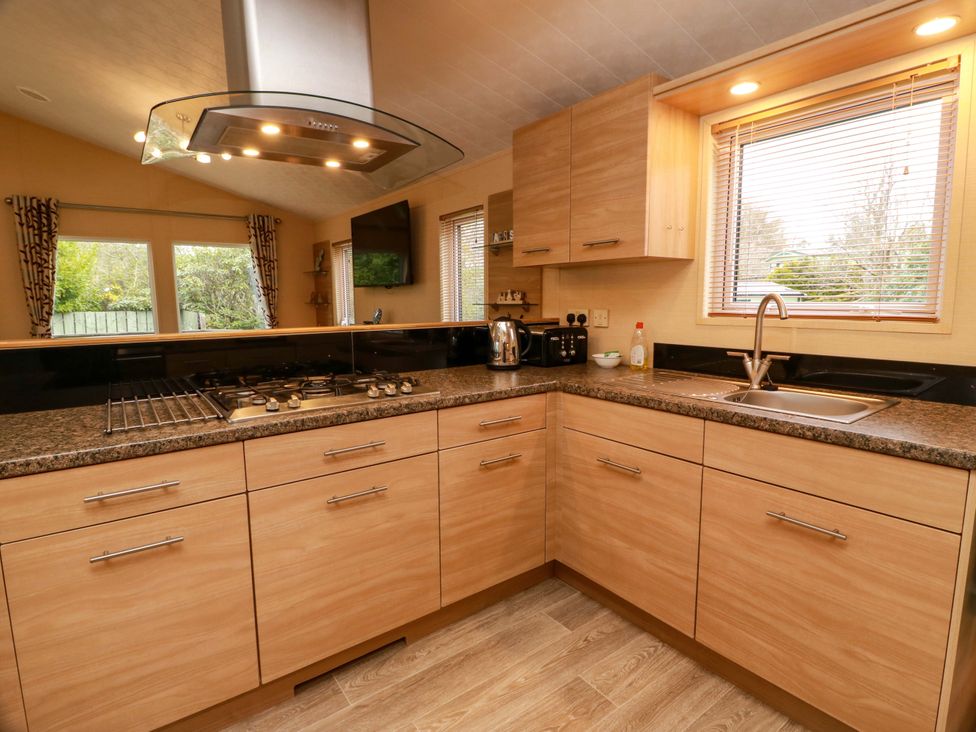 A kitchen with wooden cabinets and appliances at L21 Coastal Kippford Kippford near Sandyhills