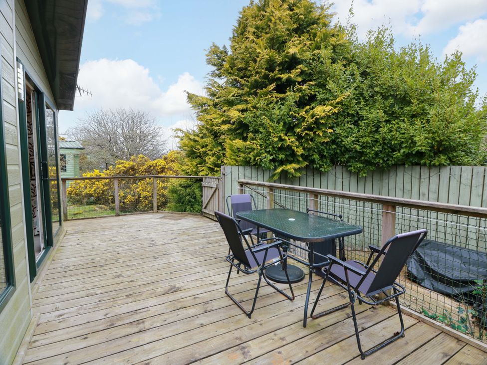 A wooden deck with a table and chairs at L21 Coastal Kippford in Kippford near Sandyhills