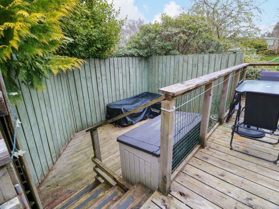 A garden with a wooden deck, table, chairs, and a storage box at L21 Coastal Kippford Kippford near Sandyhills