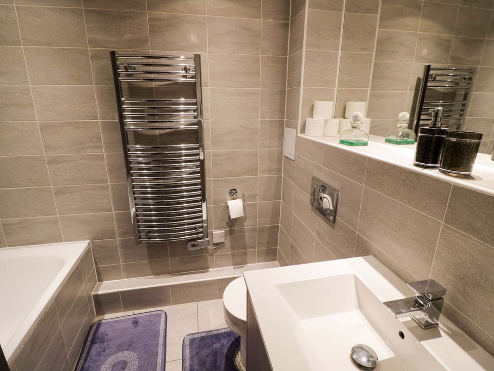 A bathroom featuring a bathtub, sink, and towel warmer at Apartment 15 in Birmingham