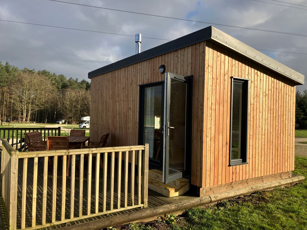 A timber cabin with a deck and wooden furniture at Sherwood - Family Pod 3 in Mansfield